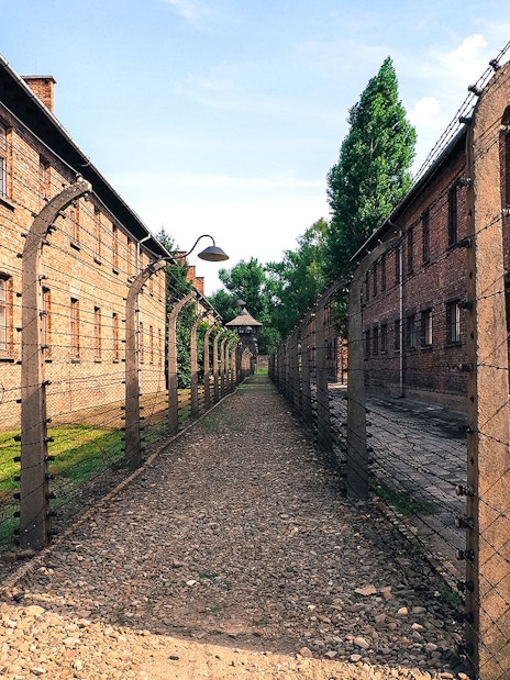 Barbed wire fence and brick buildings at Auschwitz sub-camp, Poland.