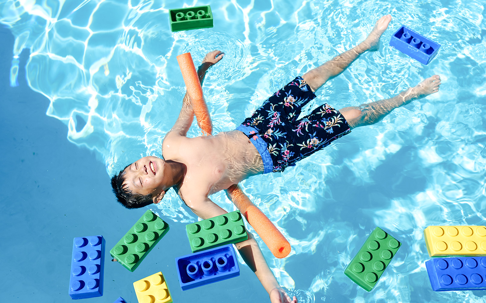 Child floating in pool with large LEGO bricks at Water Playground, Legoland New York.