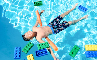 Child floating in pool with large LEGO bricks at Water Playground, Legoland New York.