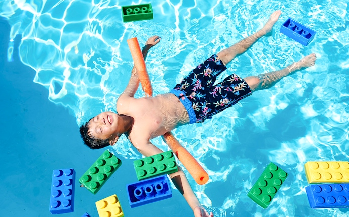 Child floating in pool with large LEGO bricks at Water Playground, Legoland New York.