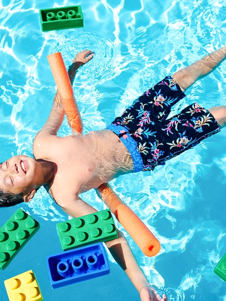 Child floating in pool with large LEGO bricks at Water Playground, Legoland New York.