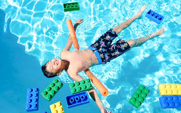 Child floating in pool with large LEGO bricks at Water Playground, Legoland New York.