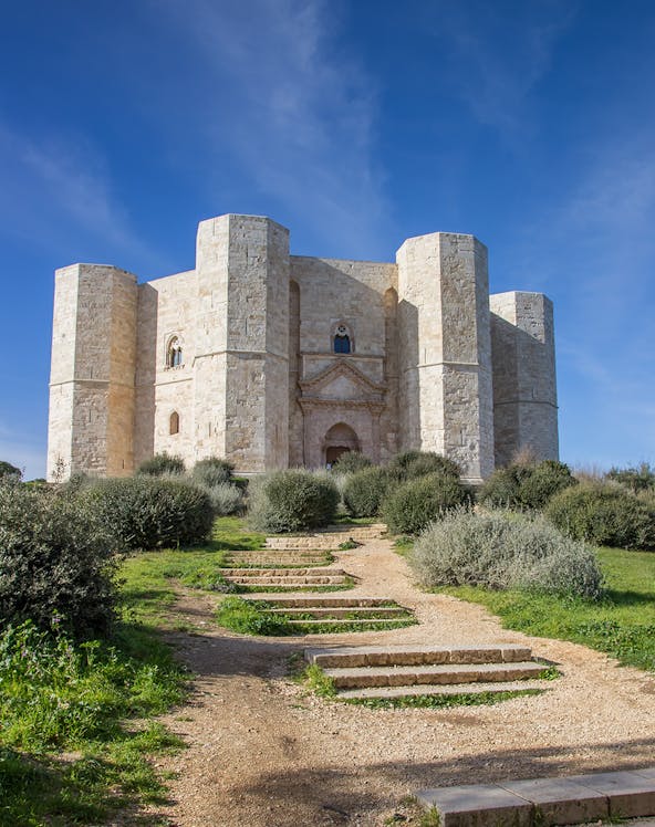 Castel del Monte in Italy with stone path leading to the entrance.