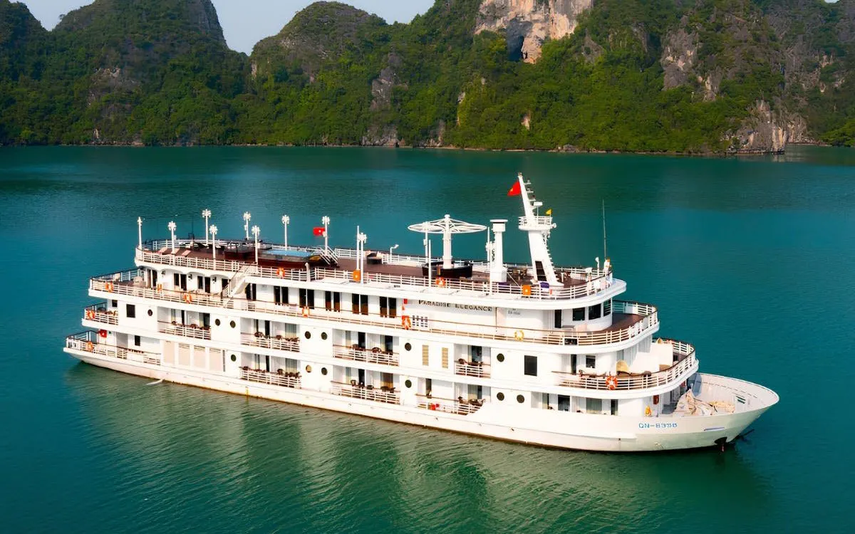 5-star cruise ship sailing in Ha Long Bay with limestone cliffs in the background.