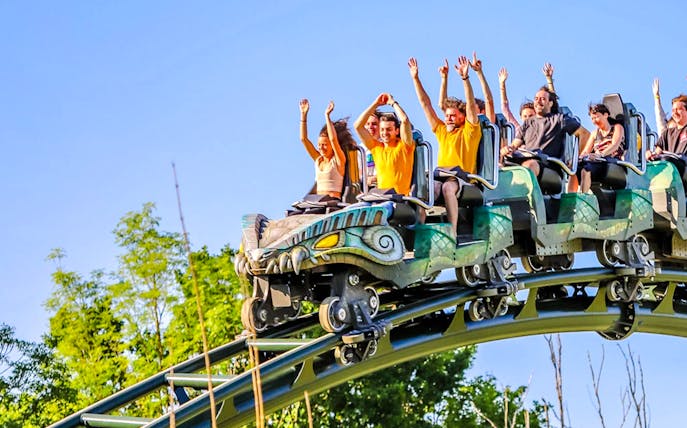 Kondaa roller coaster with riders raising hands on a sunny day.