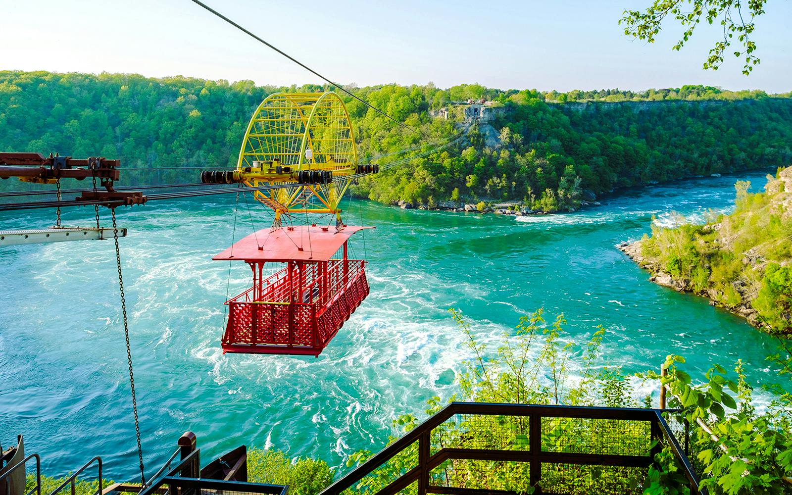 Aerial cable car over Niagara Whirlpool with lush green surroundings.