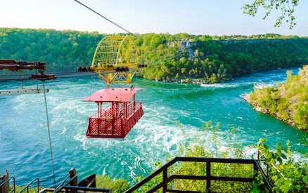 Aerial cable car over Niagara Whirlpool with lush green surroundings.