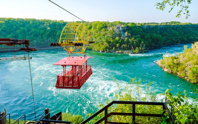 Aerial cable car over Niagara Whirlpool with lush green surroundings.