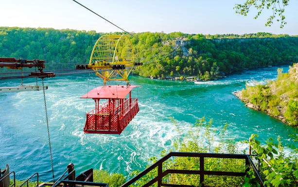 Aerial cable car over Niagara Whirlpool with lush green surroundings.