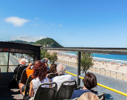 Busrundfahrt mit offenem Oberdeck entlang des Strandes La Concha in San Sebastián, Spanien.