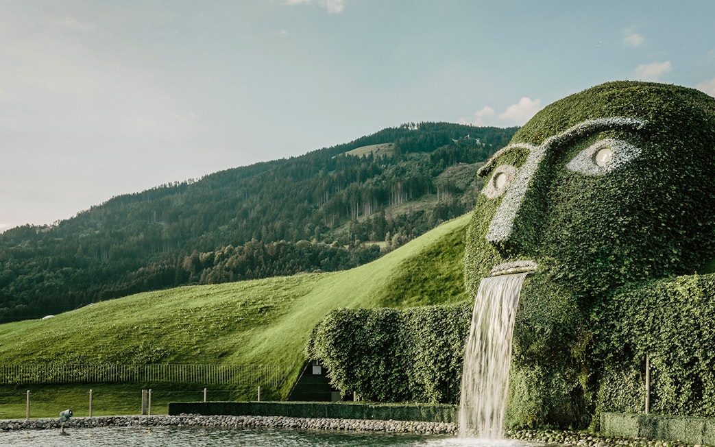 Giant grass-covered head with waterfall at Swarovski Crystal Worlds, Austria.