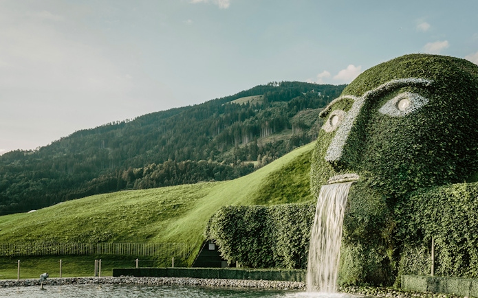Giant grass-covered head with waterfall at Swarovski Crystal Worlds, Austria.