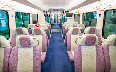 Interior of Hong Kong Airport Express train with purple seats and passenger.