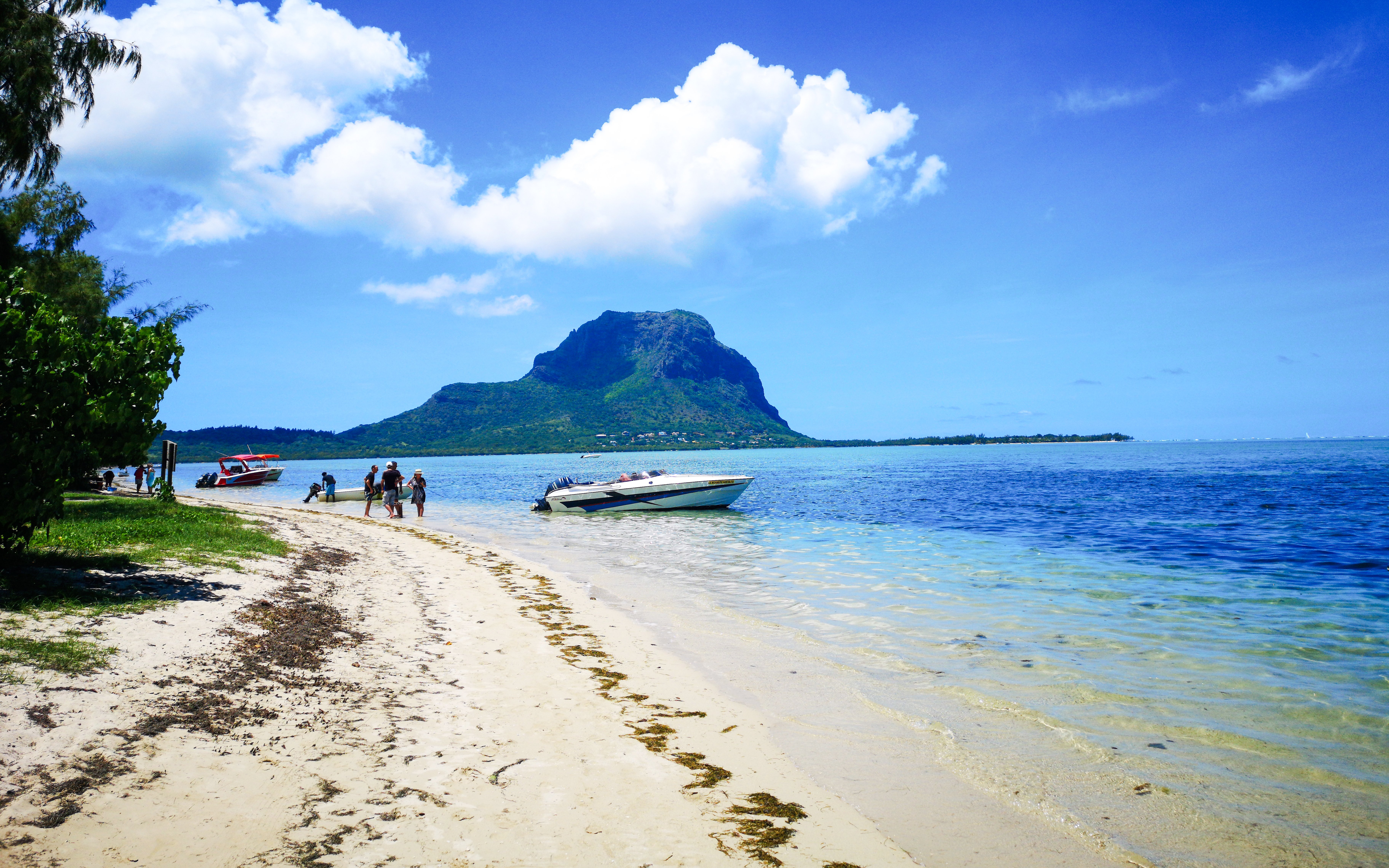 Boats anchored near Île aux Bénitiers beach, Mauritius, with Le Morne Brabant in the background.