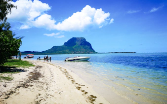 Boats anchored near Île aux Bénitiers beach, Mauritius, with Le Morne Brabant in the background.