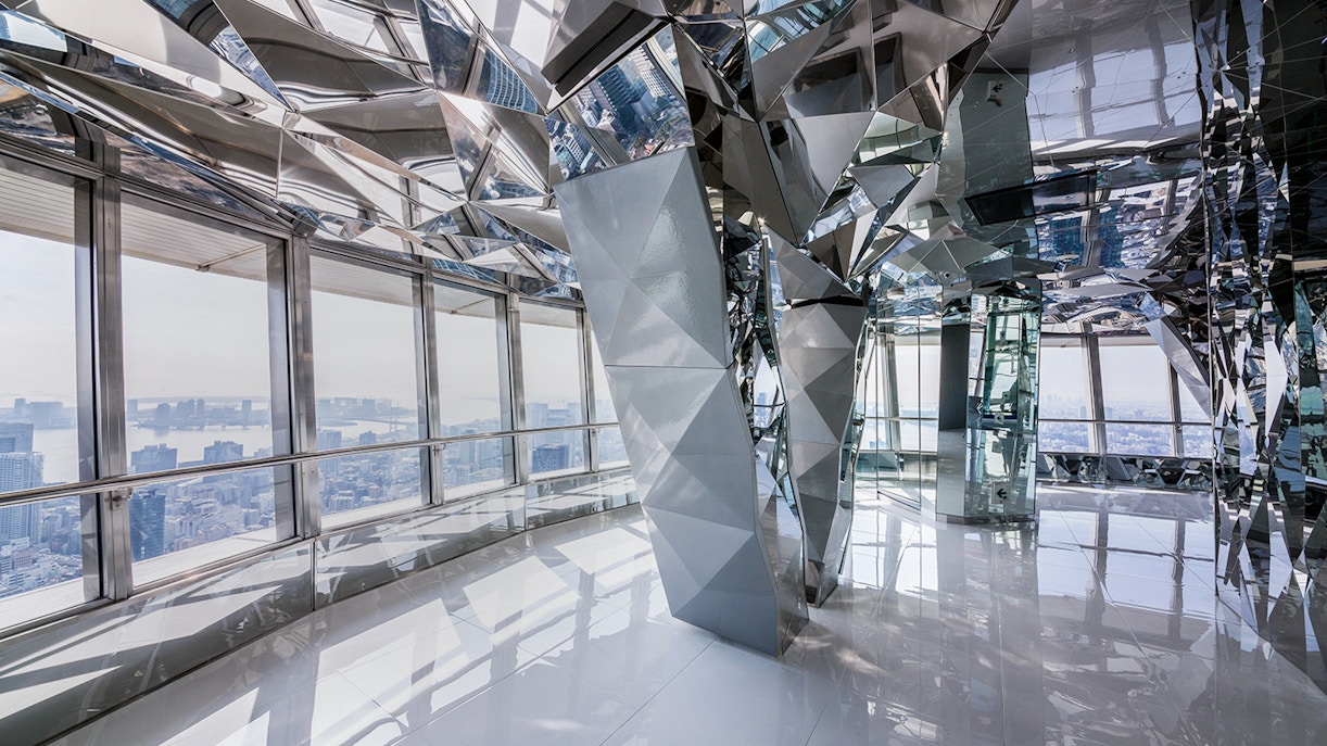Upper deck of Tokyo Tower with mirrored interior and city view.