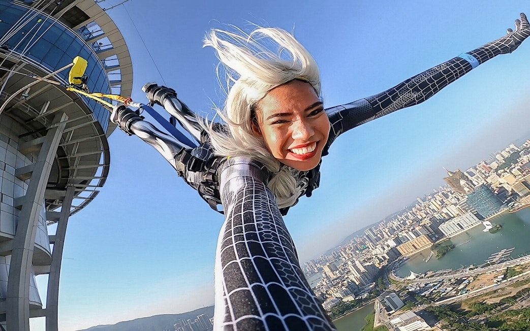 Person bungee jumping from Skypark Macau by AJ Hackett with cityscape view.