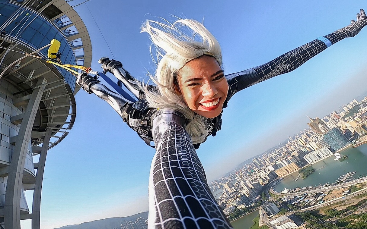 Person bungee jumping from Skypark Macau by AJ Hackett with cityscape view.