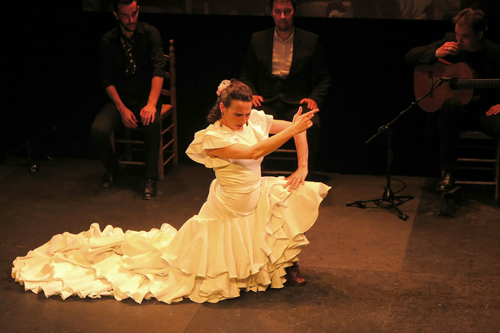 Flamenco dancer performing at Triana Theater with musicians in the background.