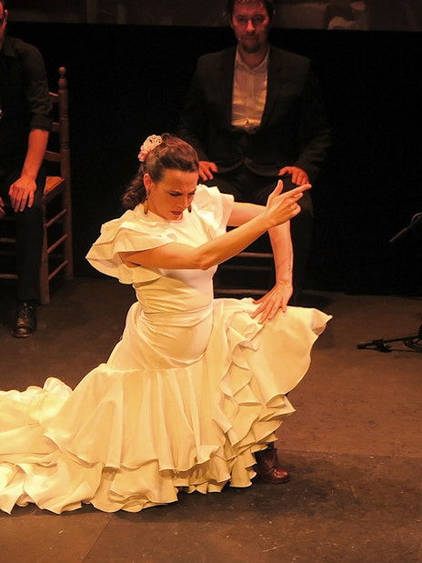 Flamenco dancer performing at Triana Theater with musicians in the background.