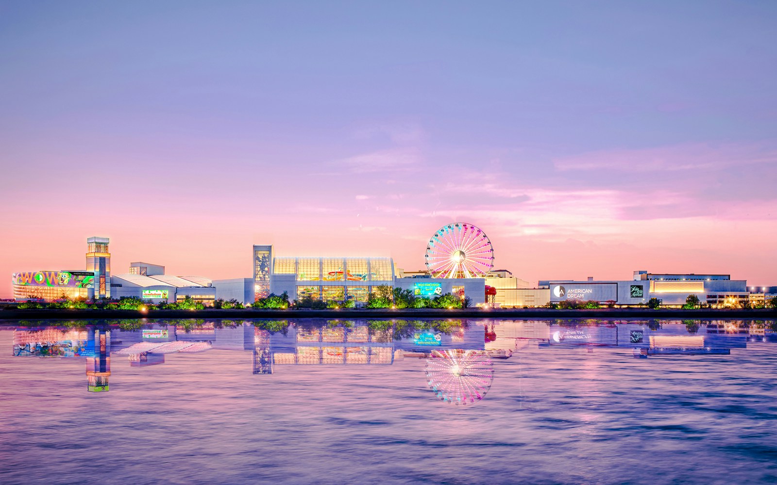 Nickelodeon Universe theme park rides at sunset, New York City skyline in the background.