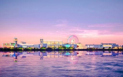 New York City sunset view with Ferris wheel and waterfront reflections.