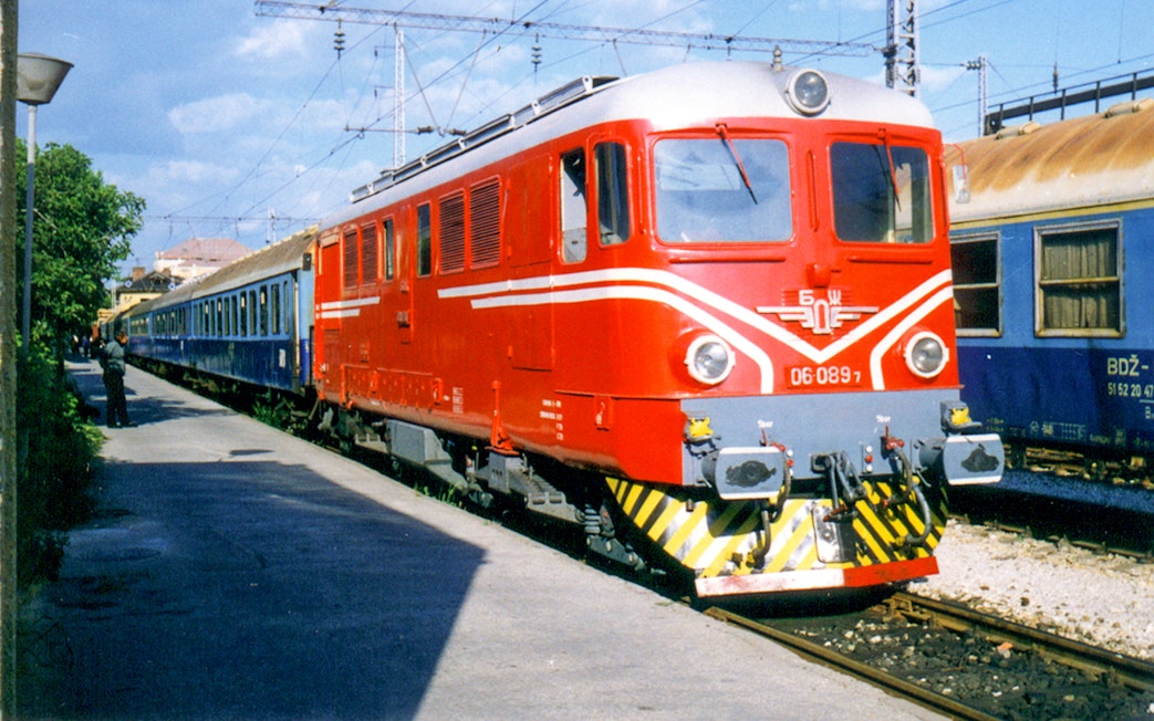 Red and blue train at a station, representing Eurail Global Flexible Pass with 1st Class Seats.