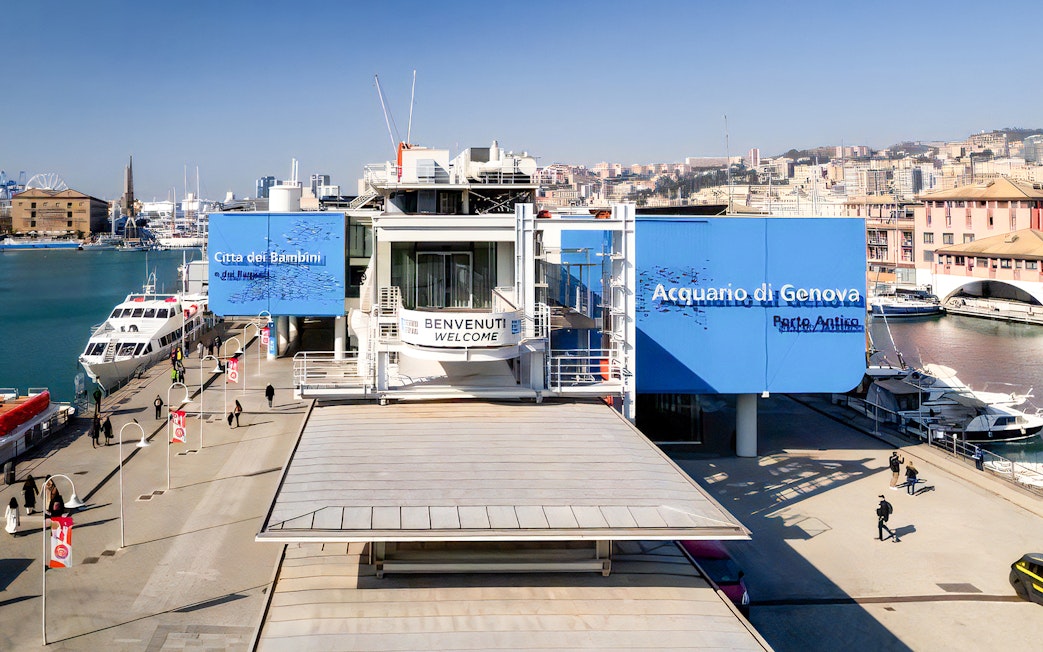 Exterior view of Aquarium of Genoa and City of Kids entrance, with nearby harbor and cityscape.