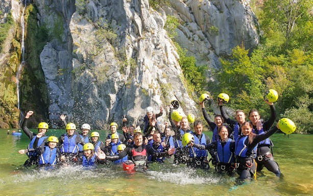Group enjoying canyoning in Cetina River with helmets and life vests, Croatia.
