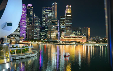 Singapore River Cruise boat on water with city skyline illuminated at night.