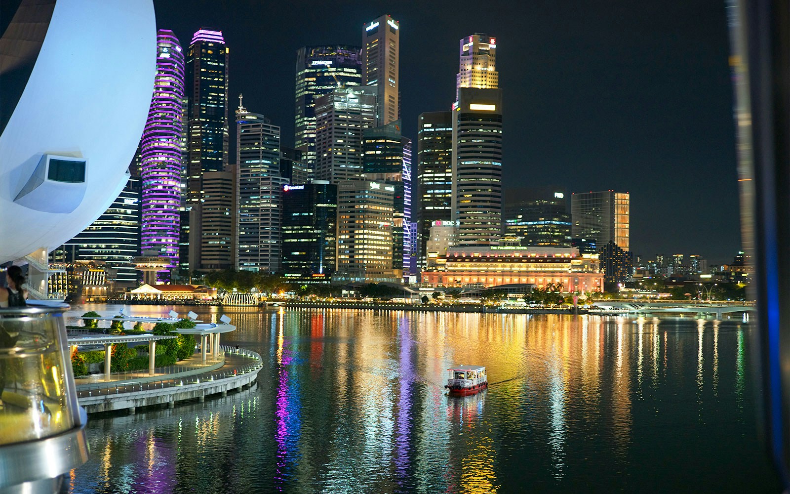 Boat cruising along the Singapore River with city skyline and historic bridges in the background.