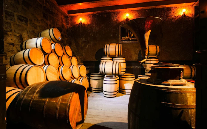 Traditional winery cellar with stacked wooden barrels for aging wine.