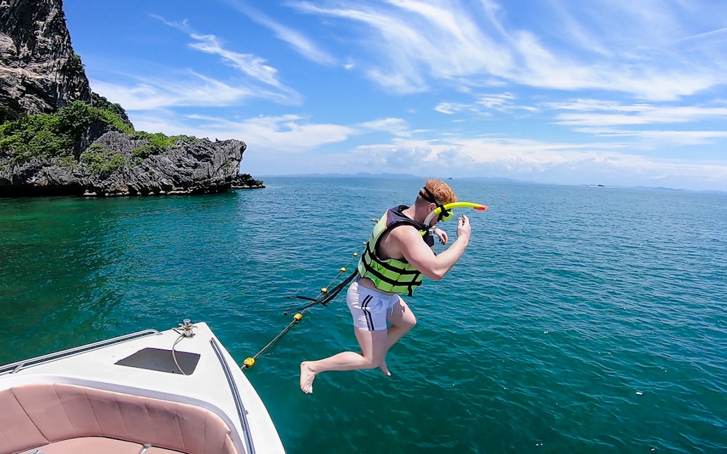 Tourist in life jacket jumping into ocean on 4-island trip from Krabi.