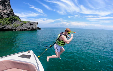 Tourist in life jacket jumping into ocean on 4-island trip from Krabi.