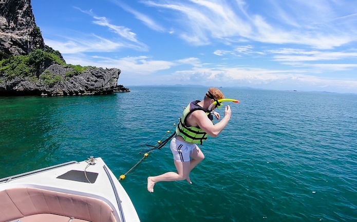 Tourist in life jacket jumping into ocean on 4-island trip from Krabi.