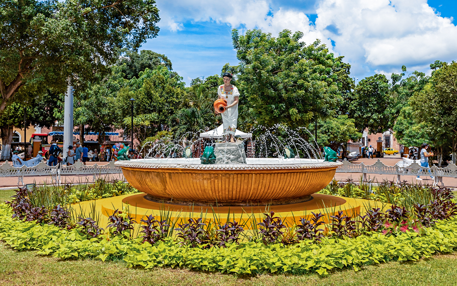 Fountain with statue in Valladolid's central park, Mexico, surrounded by greenery.
