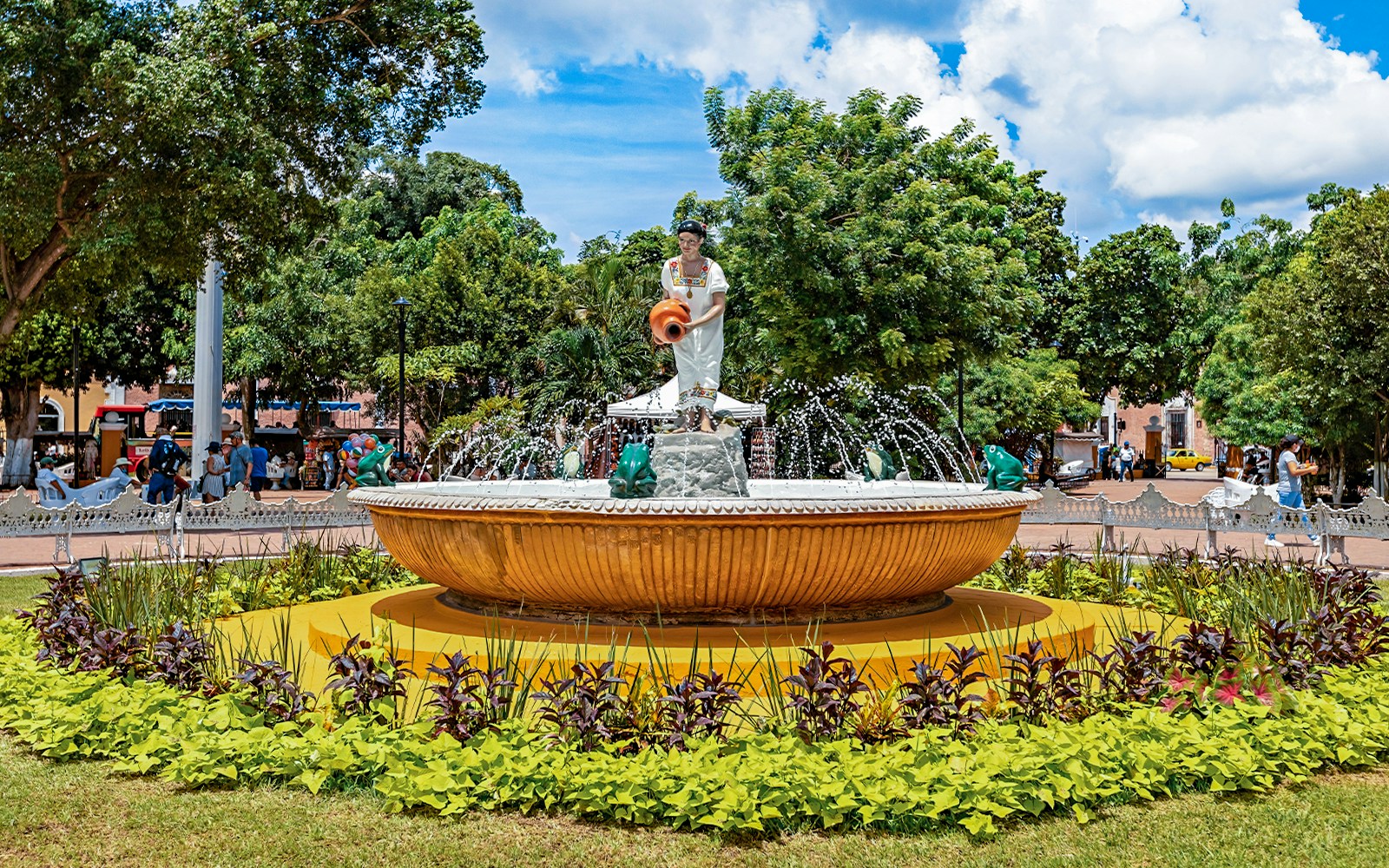 Fountain with statue in Valladolid's central park, Mexico, surrounded by greenery.