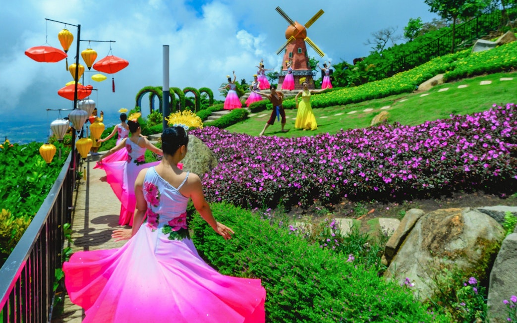 Dancers in colorful dresses perform near a windmill at Sun World Ba Den Mountain.