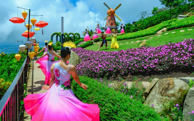 Dancers in colorful dresses perform near a windmill at Sun World Ba Den Mountain.