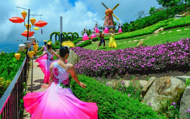 Dancers in colorful dresses perform near a windmill at Sun World Ba Den Mountain.