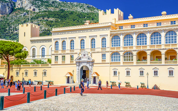 Prince's Palace in Monaco with tourists walking in the courtyard.