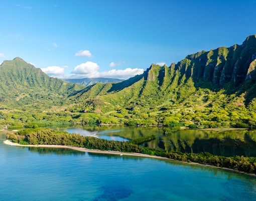 Kualoa Ranch landscape with lush green mountains and coastal waters, Oahu, Hawaii.