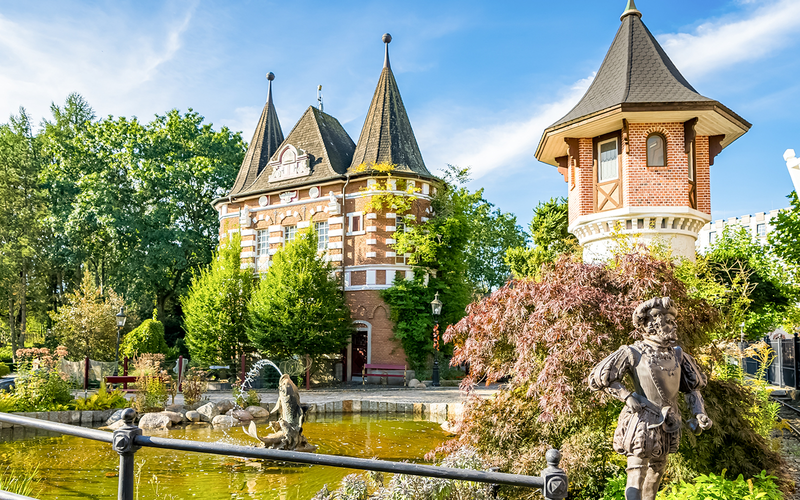 Heide Park Resort, Hamburg, features a scenic view of a castle-like building and a pond with a statue.