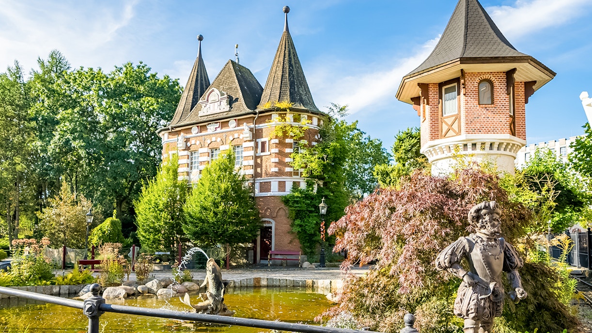 Heide Park Resort, Hamburg, features a scenic view of a castle-like building and a pond with a statue.