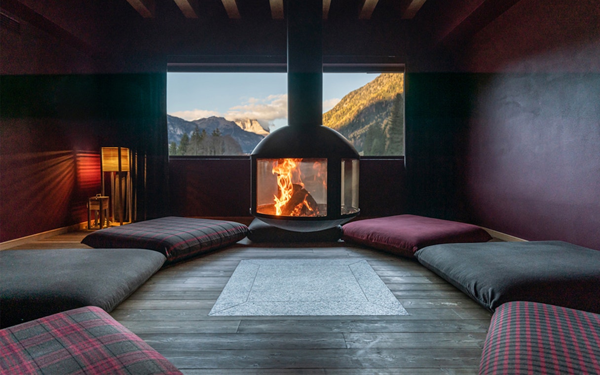 Cozy lounge with fireplace and mountain view at QC Terme Dolomiti.