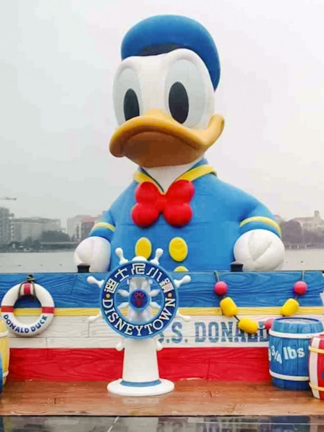 Donald Duck statue at Disneytown, Shanghai Disneyland, with waterfront view.