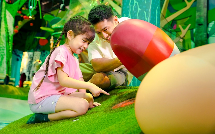 Child exploring interactive forest exhibit with adult in Forestland Curiosity Find.