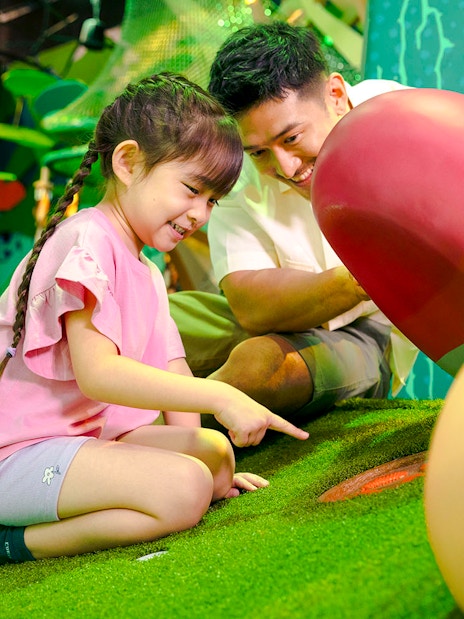 Child exploring interactive forest exhibit with adult in Forestland Curiosity Find.