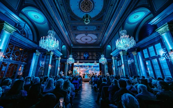 Classical concert in Vienna hall with chandeliers and audience.