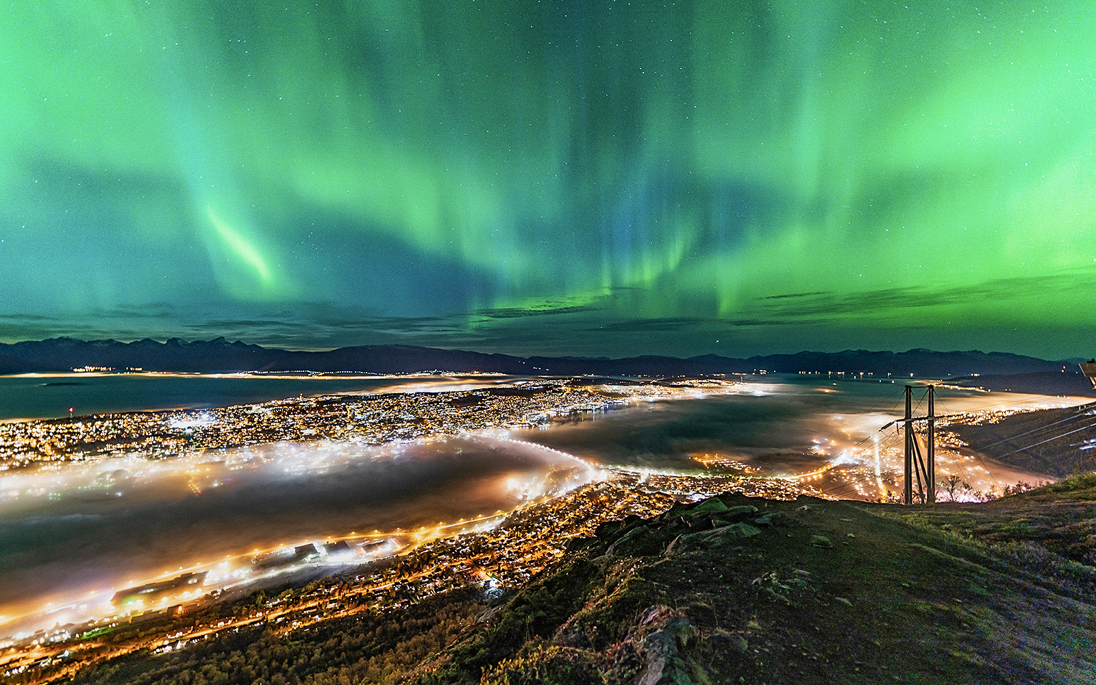Northern lights over Tromso cityscape at night.